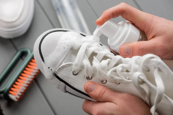 Usar un spray limpiador para limpiar una zapatilla de lona blanca — Foto de Stock