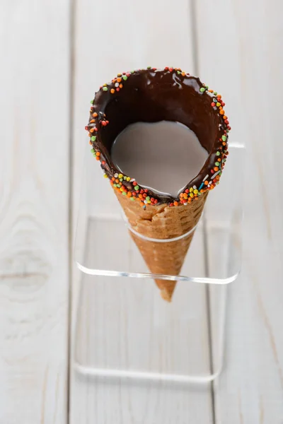Chocolate waffle cone with coffee, decorated with multicolor sprinkles
