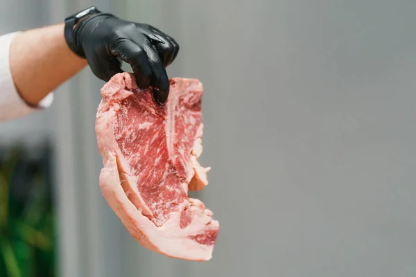 Close-up on a huge piece of perfect beef steak in hand of a chef — Stock Photo, Image