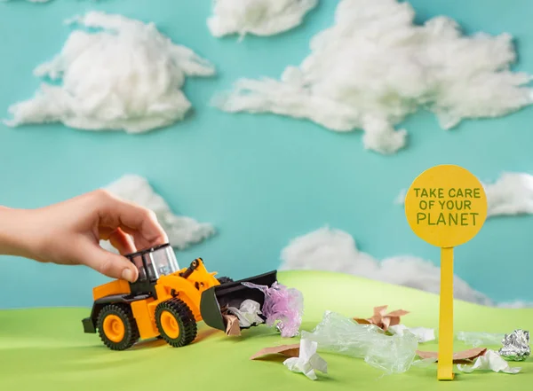 Child playing with a toy truck cleaning green lawn from trash — Stock Photo, Image