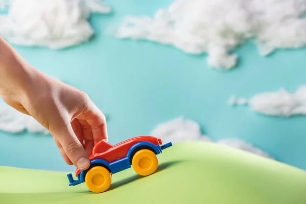 Childs hand playing with a toy car on green paper lawn — Stock Photo, Image