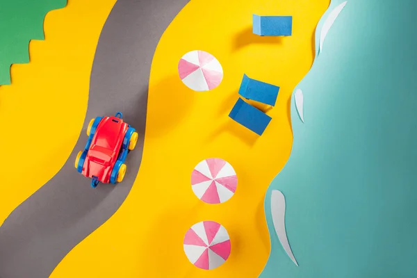 Röd leksaksbil rör sig på vägen längs stranden — Stockfoto