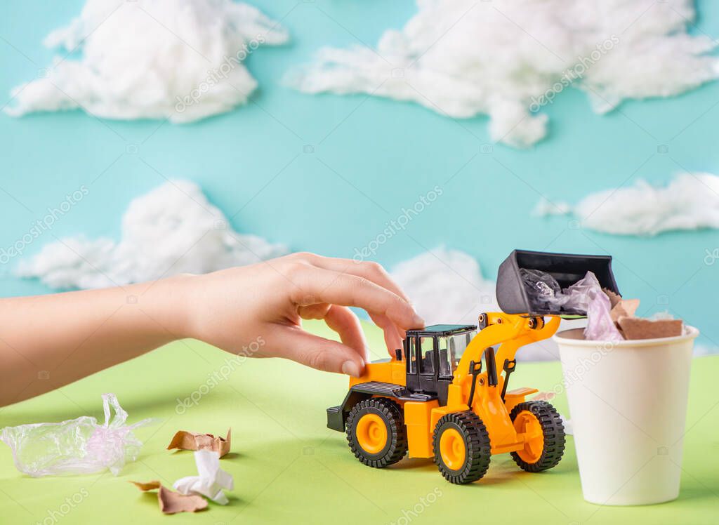 Child playing with a toy truck and collecting trash into the bin