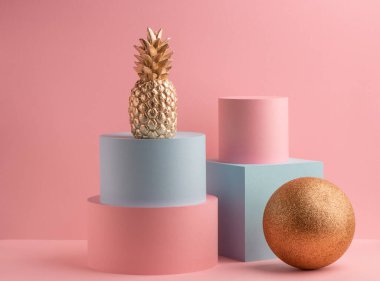 Altın ananas, simli top, yeşil küp ve pembe arka planda pembe yuvarlak kutu.