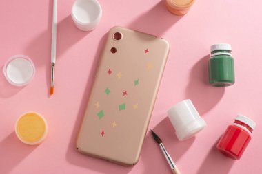 El boyaması yıldızlarla süslenmiş bej telefon kılıfı.