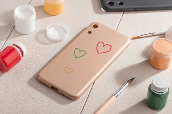 Various color hearts painted on beige phone case