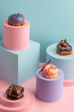 Mavi ve pembe arka planda parlak kremalı keklerin sunumu