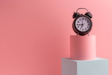 Fotokopi alanı olan pembe arkaplan üzerindeki siyah alarm saati
