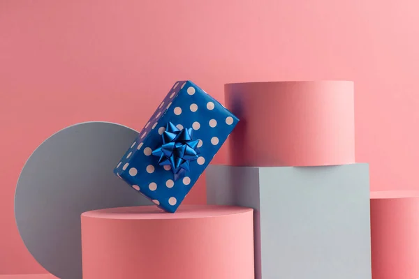 Синя точкова подарункова коробка на циліндрах та кубиках на рожевому фоні — стокове фото