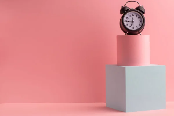 Reloj despertador vintage en cubo y cilindro sobre fondo rosa —  Fotos de Stock