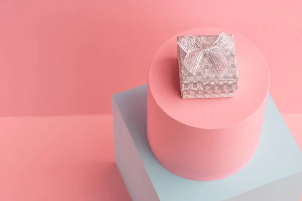 Маленька ігристий срібна подарункова коробка на рожевому фоні з копіювальним простором — стокове фото