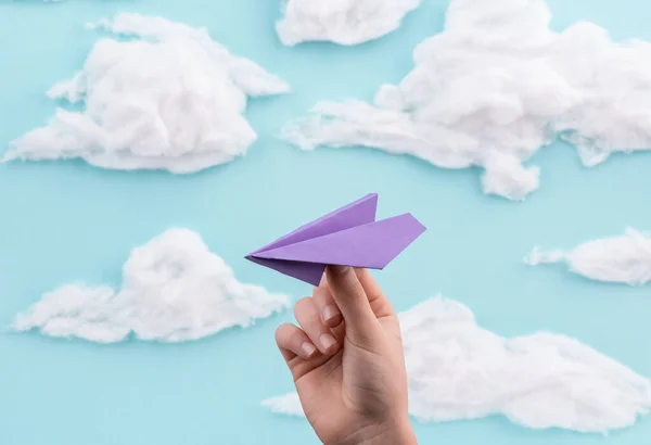 Main tenant un avion en papier violet sur fond bleu ciel fait main — Photo