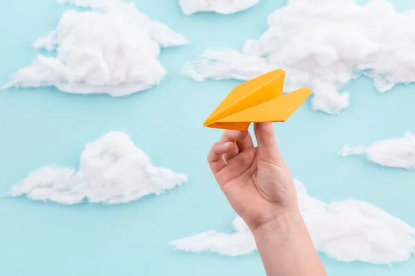 Orange papper plan i barn hand flyger genom blå himmel med moln — Stockfoto