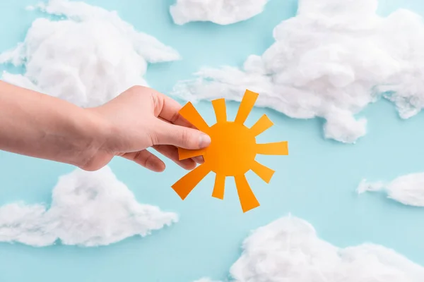 Enfant tenant un papier découpé orange soleil sur ciel bleu avec des nuages de laine de coton — Photo
