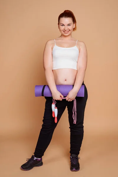 Mulher de sobrepeso posando com um tapete e uma corda de salto — Fotografia de Stock