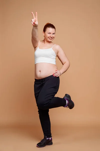 Mulher feliz mostrando sinal de vitória ao fazer exercícios de aquecimento — Fotografia de Stock