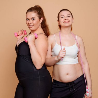 Spor salonundaki şişman kızlar, halat atlama ve dambıllarla poz veriyorlar.