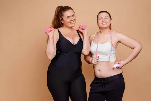 Mulheres gordas a exercitar-se num ginásio. Sorrisos felizes e forte desejo de mudar o corpo — Fotografia de Stock