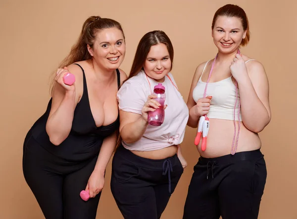 Mulheres gordas posando em fundo bege. Vestido em desgaste fitness — Fotografia de Stock