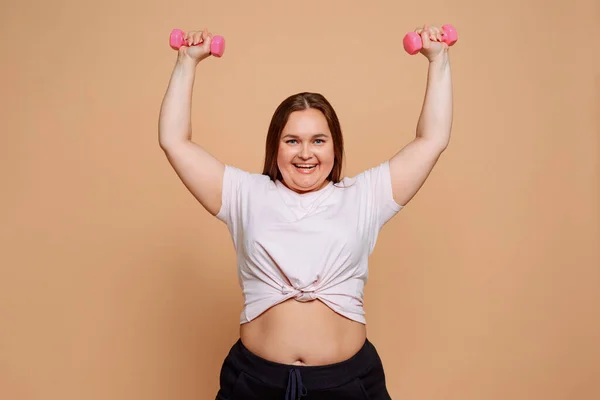 Очаровательная девушка с избыточным весом, выполняющая упражнения гантели — стоковое фото
