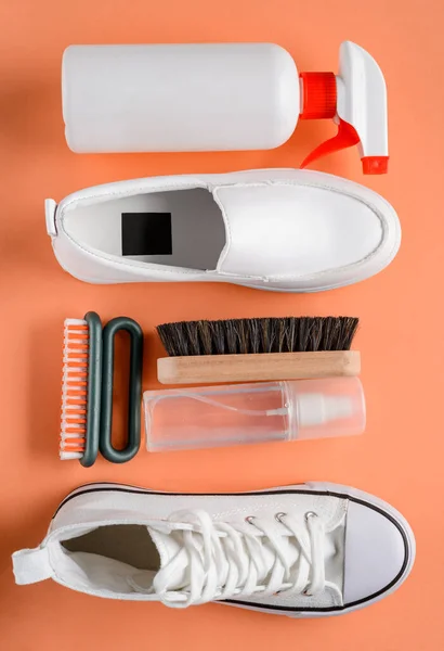 Sapatos brancos e ferramentas de limpeza em fundo laranja — Fotografia de Stock