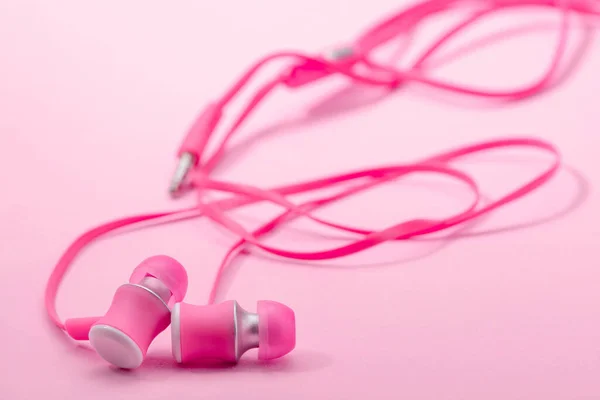 Auriculares en el oído sobre fondo rosa, enfoque selectivo — Foto de Stock