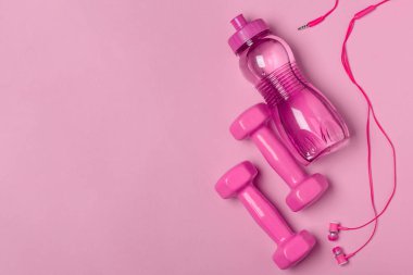Pembe arka planda dambıllar, şişeler ve kulaklıklar.