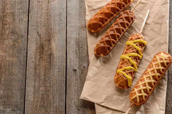 Corn dogs on kraft paper on wooden background — Stock Photo, Image