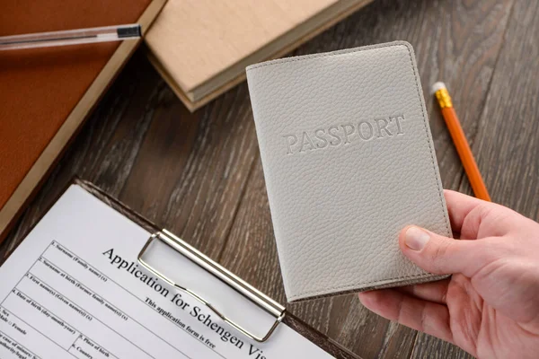 Hand in Hand einen Reisepass, im Hintergrund ein Antragsformular — Stockfoto