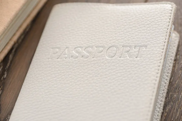 Крупный план по паспорту в белом чехле на деревянном столе — стоковое фото