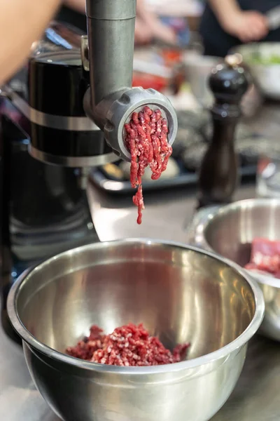 Gehakt rauw vlees dat uit een elektrische molen komt — Stockfoto