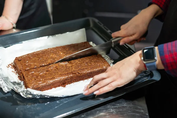 Vrouw snijden vers gebakken brownie cake in twee — Stockfoto