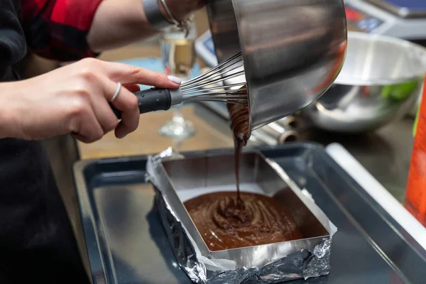 Perempuan menuangkan adonan coklat ke dalam panci — Stok Foto