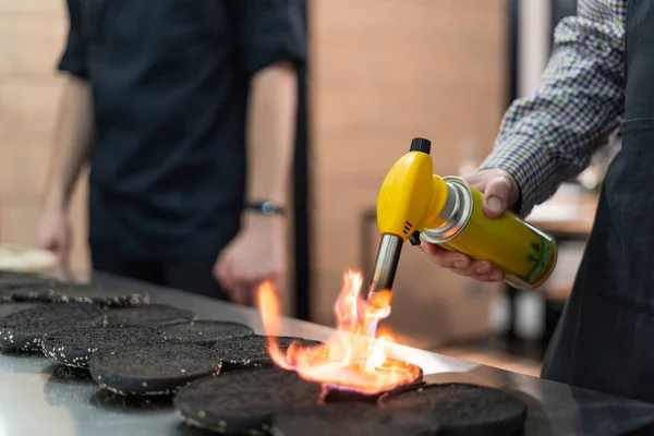 Chef met behulp van een brander te korst hamburger broodjes — Stockfoto