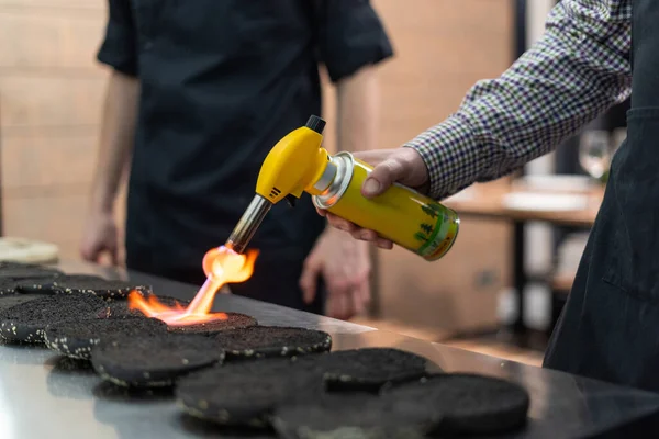 Mand ved hjælp af et køkken fakkel til at gøre boller mere sprøde - Stock-foto
