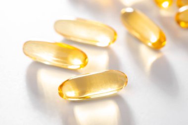 Beyaz arkaplandaki morina yağı kapsüllerine yakın plan