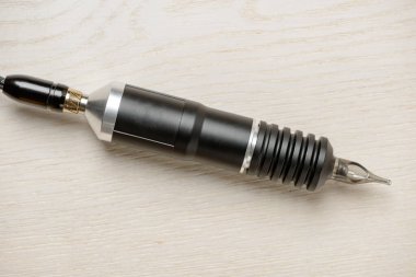 Tahta masadaki dövme kalem makinesine yaklaş.