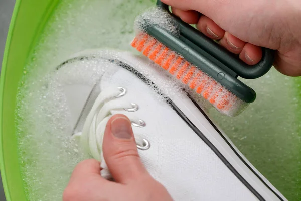 Hombre limpiando zapatillas de lona blanca, de cerca — Foto de Stock