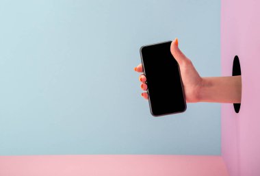 Mavi ve pembe arkaplanda bir telefon tutan kadınlar.