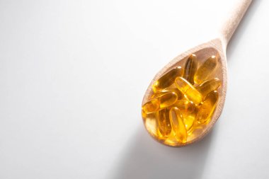 Beyaz arka planda tahta kaşık Omega 3 kapsülleri