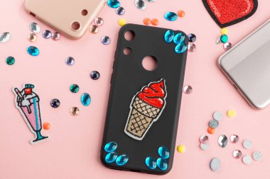 Siyah telefon kılıfında mavi elmaslar ve kırmızı dondurma arması.