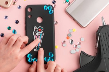 Yapay elmaslar takan ve yapıştırıcı tabancasıyla işlemeli kokteyl yaması yapan bir kız.