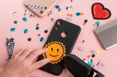 Siyah telefon kılıfına güneş ışığı bandı yapıştıran bir kız