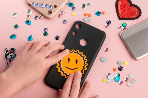 Girl putting a sun smile patch onto black phone case — Stock Photo, Image