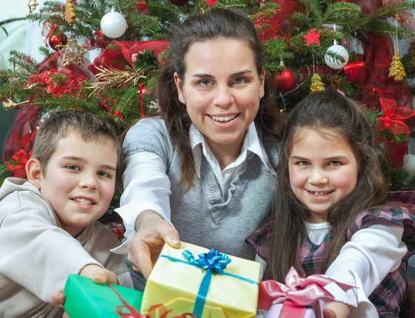 クリスマスツリーの前で贈り物を交換する家族 — ストック写真