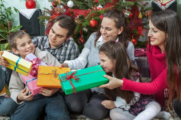 Family exchanging gifts in front of Christmas tree — Stock Photo, Image