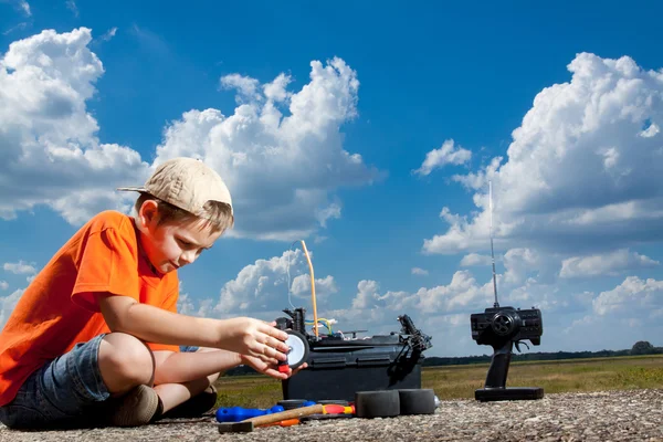 Liten pojke repaire radio kontroll bilen utomhus nära fältet — Stockfoto