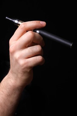 Siyah bir arka plan üzerinde elektronik sigara tutan el