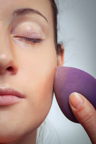 Stichting door sponge op gezicht voor make-up toe te passen — Stockfoto