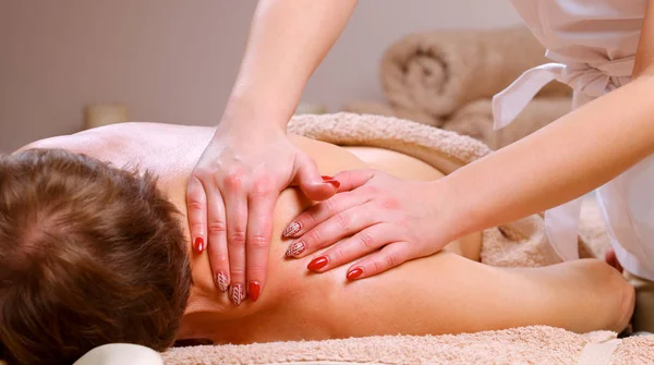 Massagetherapeutin massiert Schultern und Rücken eines Mannes — Stockfoto
